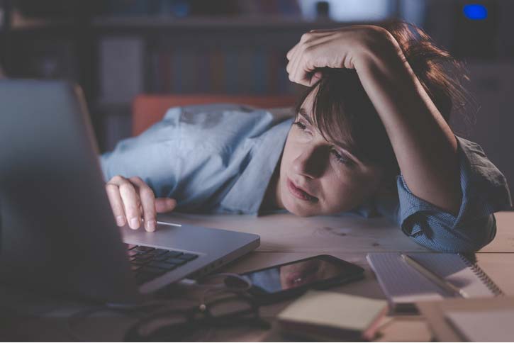 A woman tries to stay awake at her desk.