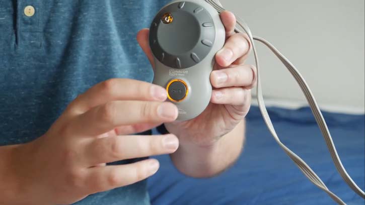 A man shows a heated blanket controller.