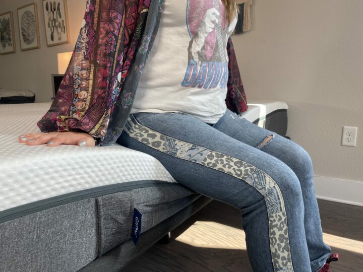 A woman sits on the side of the Emma mattress