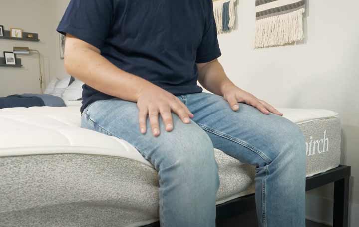 man sitting on the edge of the Birch mattress