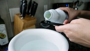 pouring bleach into bowl of water