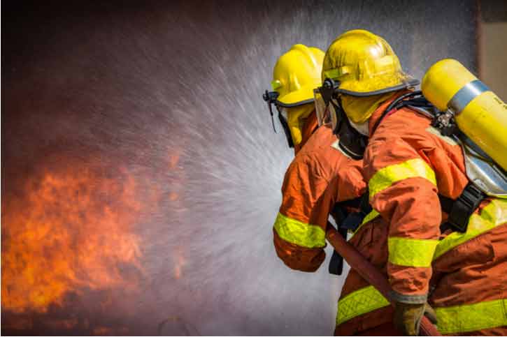 Firefighters spray water into a fire.