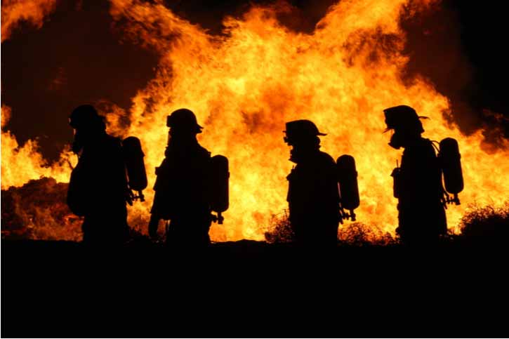 Firefighters walk by a raging fire.