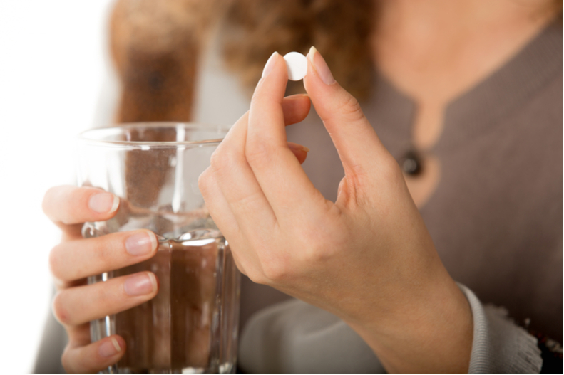 Woman Holding Sleep Aid and Glass of Water