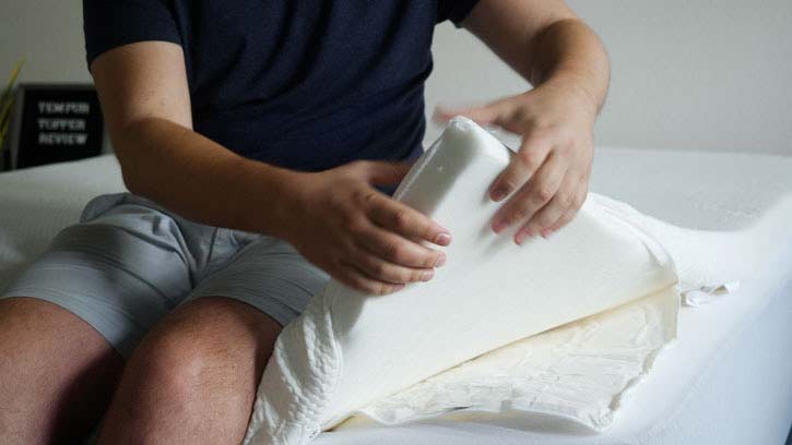 A man squeezes the corner of the TEMPUR Adapt topper.
