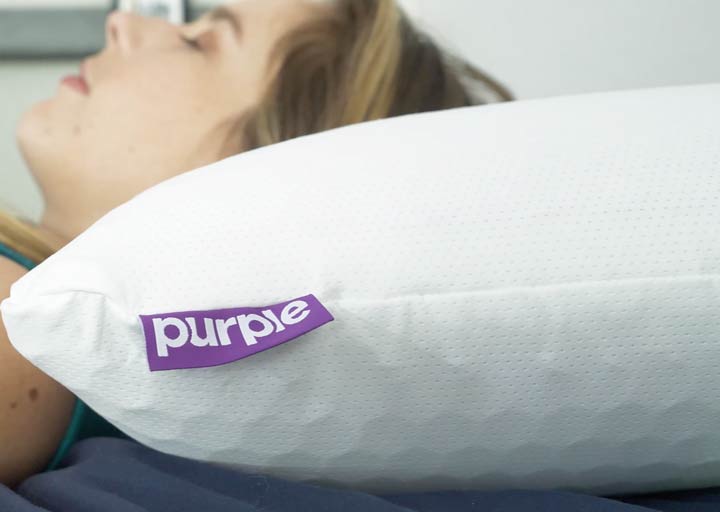 A woman rests on her back using the Purple Harmony pillow.