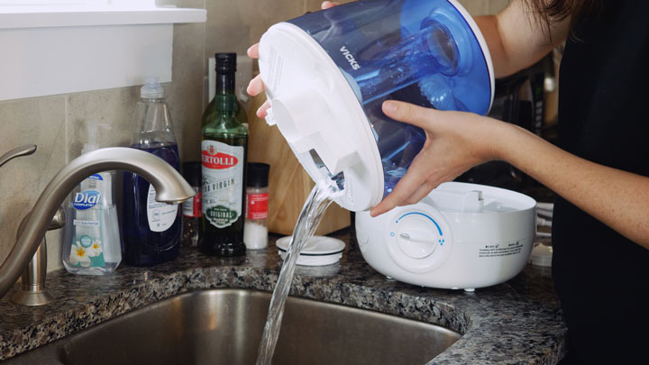 A woman pours out water from a humidifier's water tank.