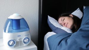 An image of a woman sleeping next to the Vicks Starry Night humidifier.