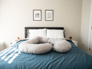 The Leachco Snoogle Pillow placed on a bed.