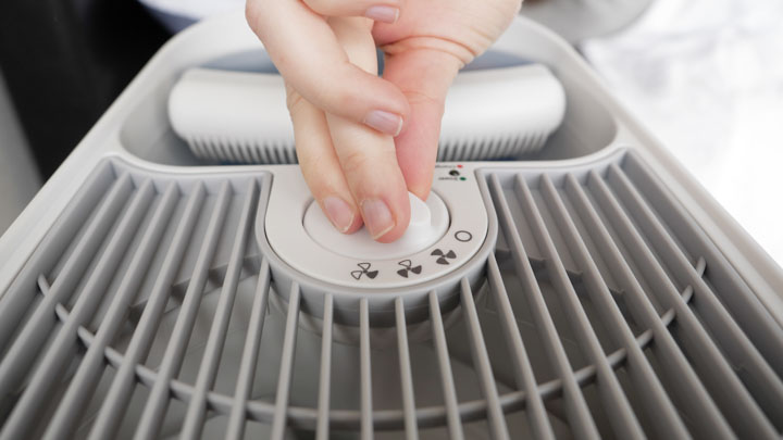 A close up image of a hand turning the dial on a humidifier.