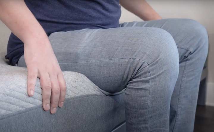 A man sits near the edge of the Casper mattress