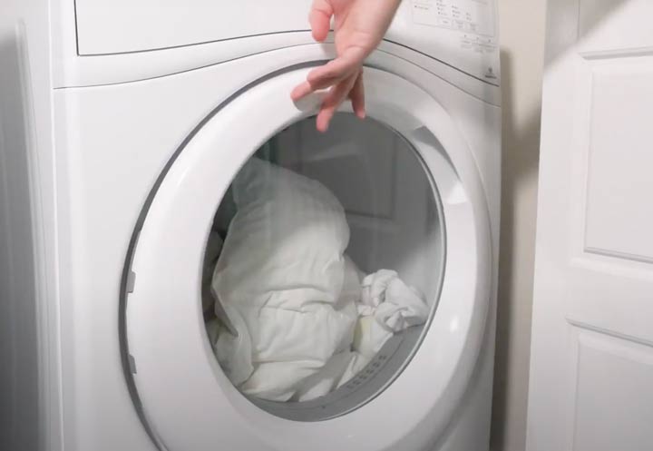 The Best Linen Sheets: A woman puts sheets into a washing machine.