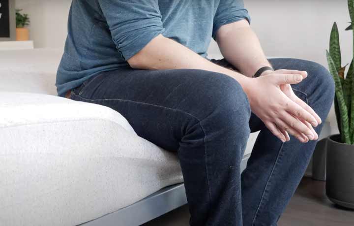 A man sits on the edge of the Casper Hybrid mattress