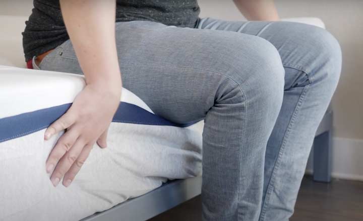 man sitting on the edge of the Helix Midnight mattress