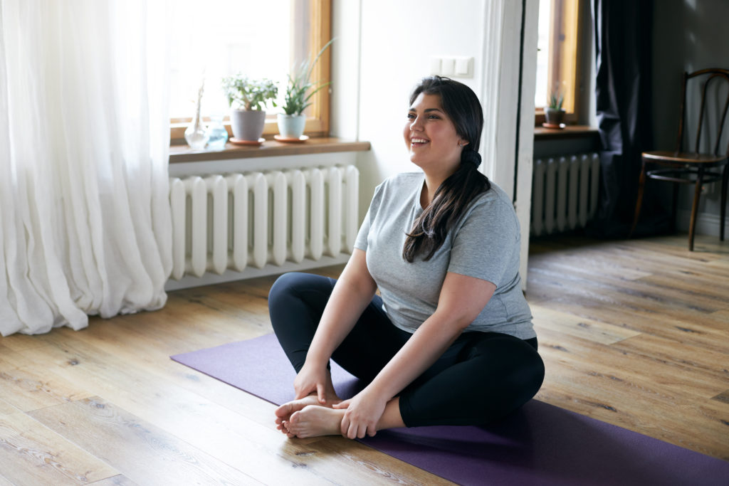 A woman does yoga on a mat in a room