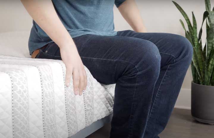 man sitting on the edge of the Leesa Sapira Hybrid mattress