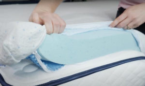 A woman pulls back the cover of the ViscoSoft topper, revealing the memory foam inside.