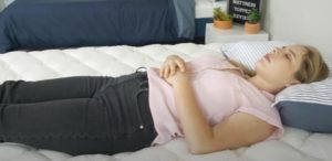 A woman rests on her back using the Helix Plush Topper.