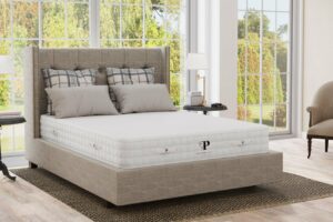 A latex mattress on a bed frame in a windowed room