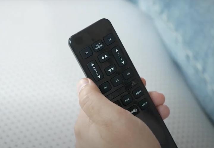 A close-up of a hand holding the remote for the Nectar Adjustable Base.