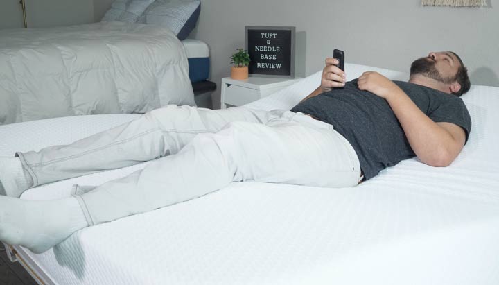 A wide shot of a man adjusting the Tuft & Needle base while he lies down