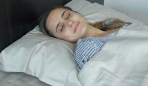 woman sleeping in bed with Boll and Branch sheets woman sleeping in bed with Boll and Branch sheets