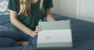 The Best Percale Sheets - An image of a woman sitting on a bed with the sheets in their packaging.
