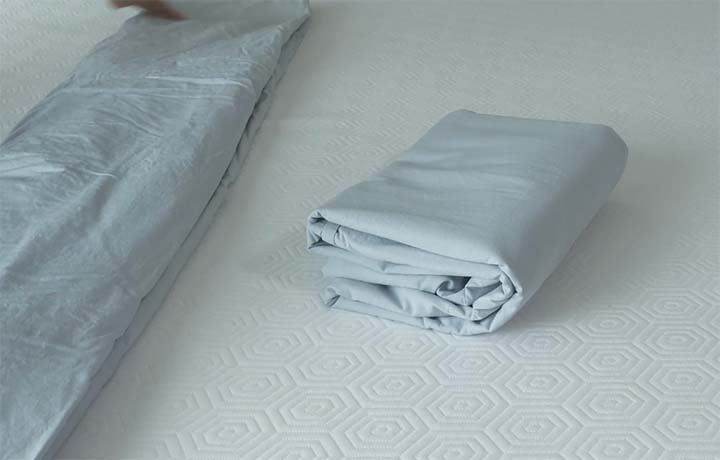 The Parachute percale sheets folded up on a bare mattress.