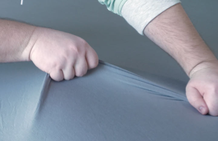 A man stretches the gray colored Purple SoftStretch Sheets