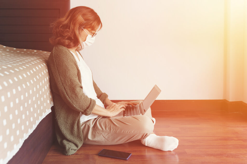 Woman wearing face mask working from bedroom