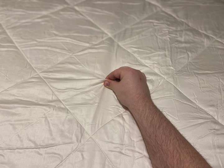 Cozy Earth Comforter - A man pinches the fabric on the comforter.