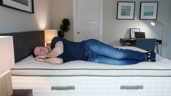 A wide shot of a man side sleeping on the Avocado mattress