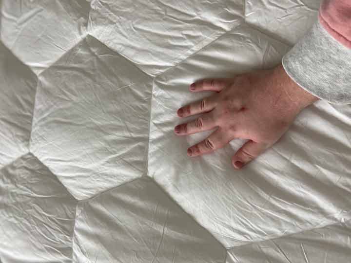 Layla Comforter Review - A man rubs his hands across the Layla Comforter.