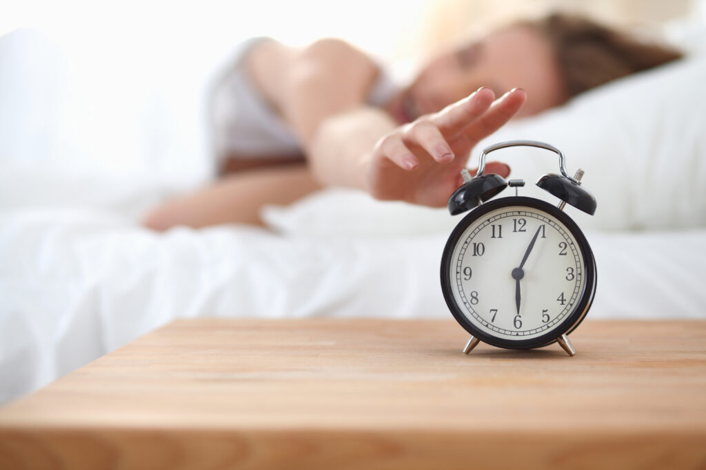 woman reaching to turn off alarm clock