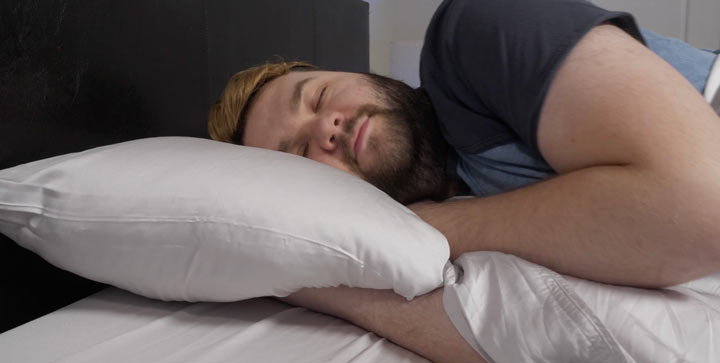 A man sleeps on his side with the puffy bamboo sheets.