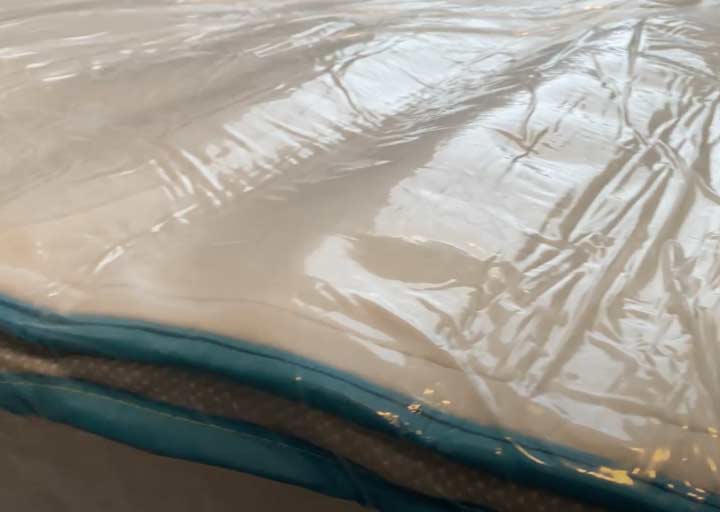 A close-up of a bed in a box mattress still in the plastic