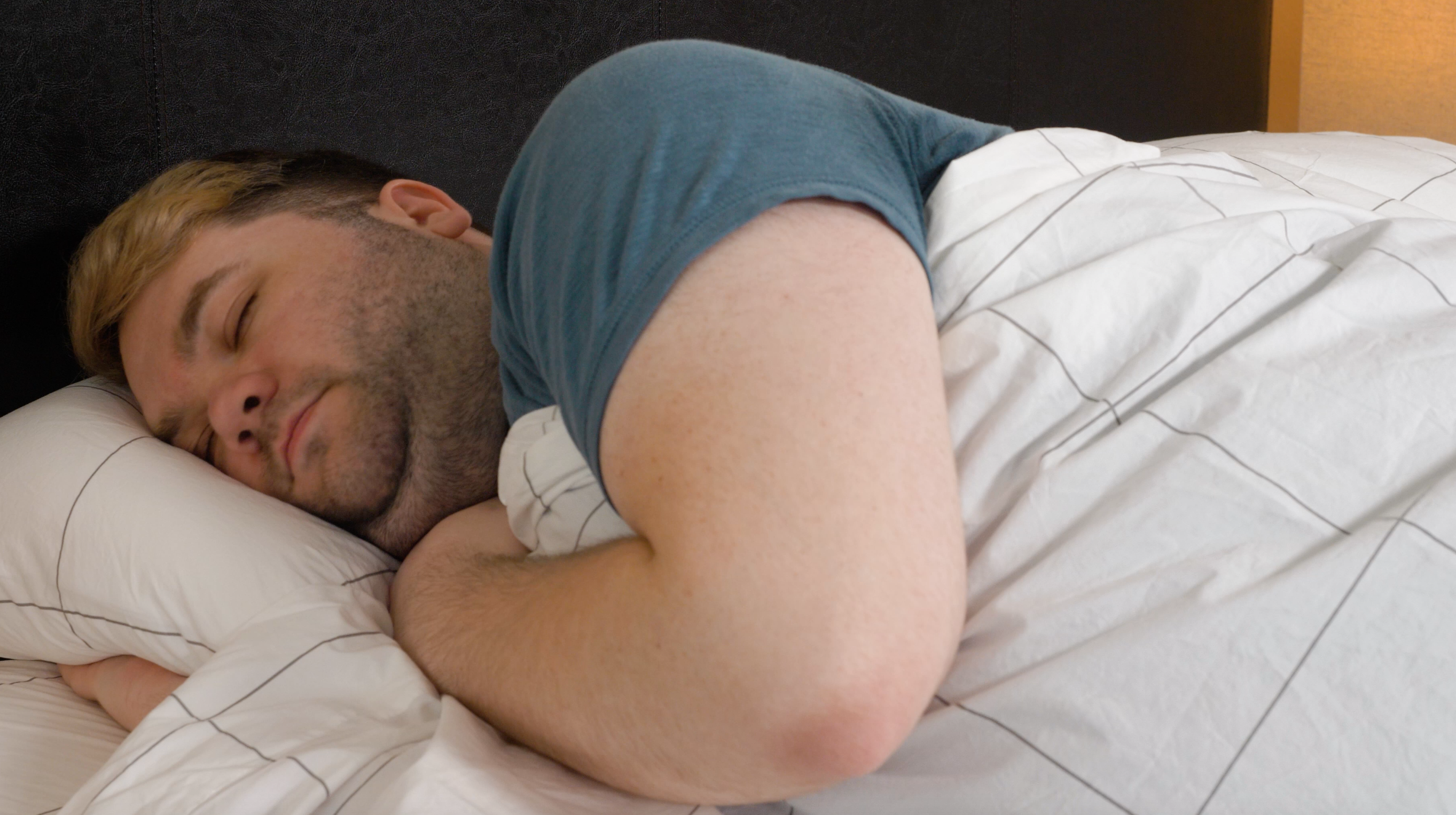 A man sleeps on his side on the Brooklinen Classic Sheets