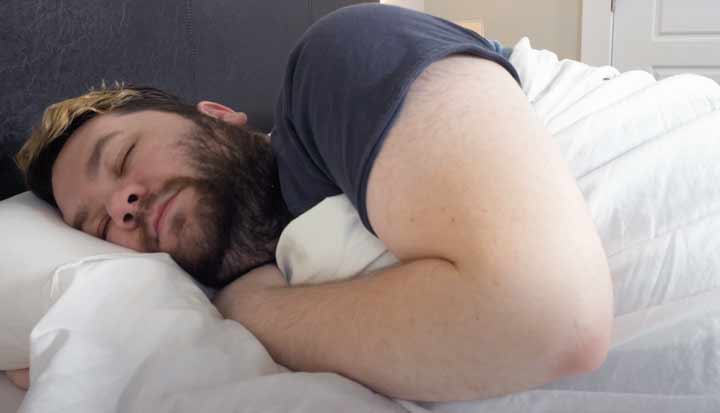 A man sleeps on his side on Saatva Organic Sateen Sheets.