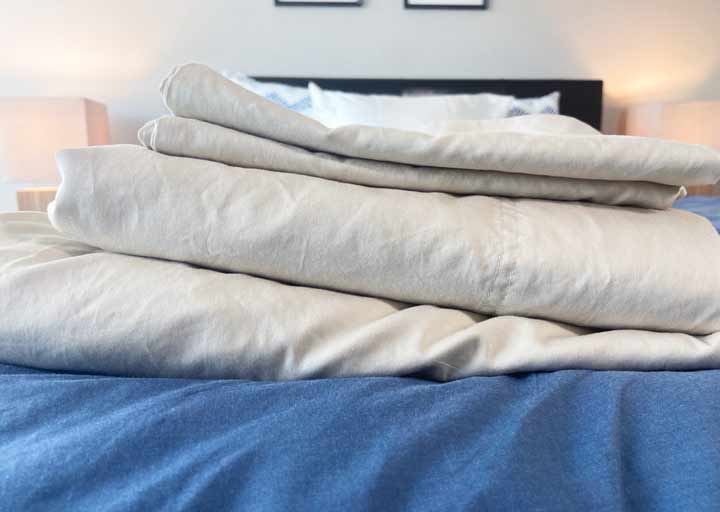 A stack of Brooklyn Bedding Sheets on a bed. 