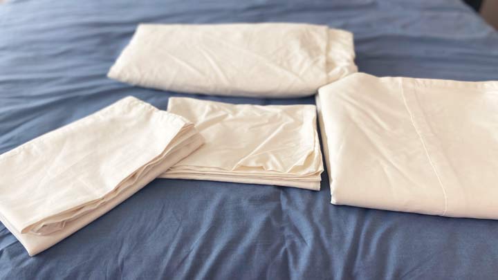 The pieces that make up the Boll & Branch percale hemmed sheets sit on a bed.