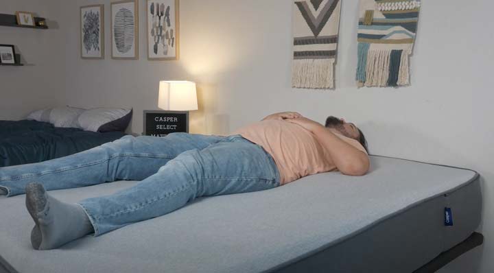 A man sleeps on his back on the Casper Select mattress