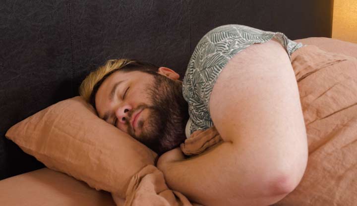 A man sleeps on his side with the Parachute linen sheets