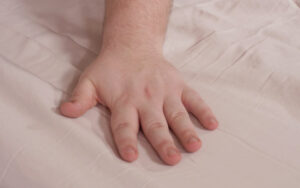 A hand brushes across the Parachute Sateen Sheets.