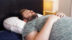 A man sleeps on his back on the Bear Contour Pillow.