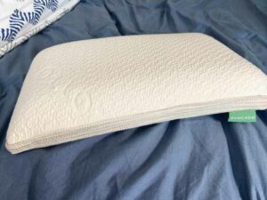 A picture of the Avocado Mini Molded Latex Pillow on a bed.