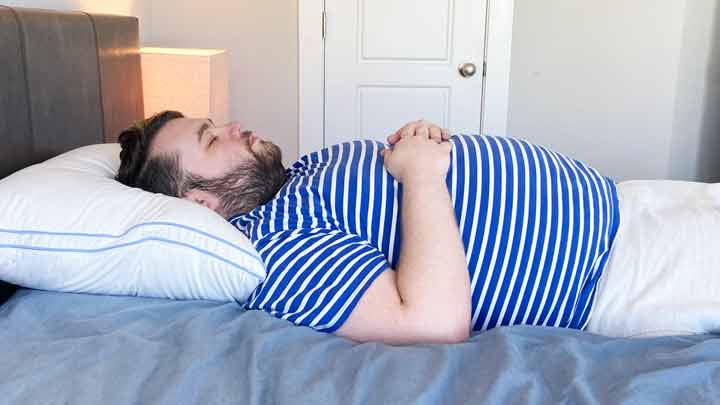 A man sleeps on his back with the Henrie Pillow