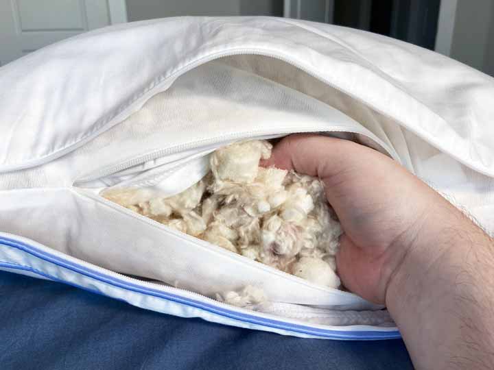 A person sticks their hand in the shredded foam inside of the Henrie Pillow