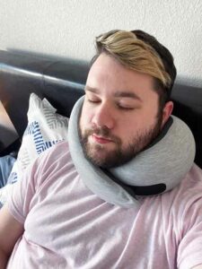 A man sleeps with the Ostrichpillow Go Neck pillow.