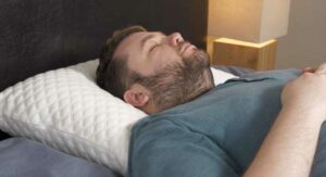 A man sleeps on his back on a Nolah Squishy Pillow