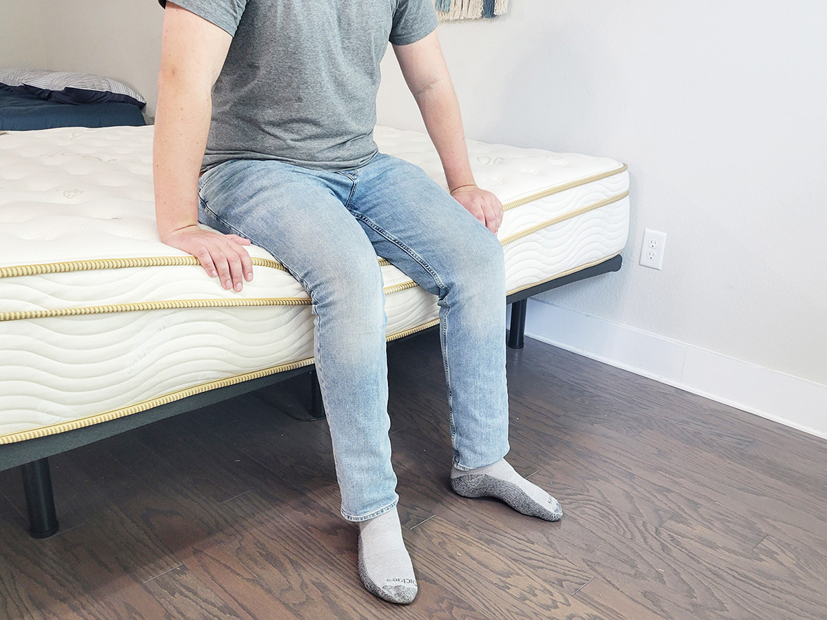 man sitting on the edge of the Saatva mattress